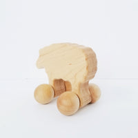 Light wood sheep toy with ball wheels on white background