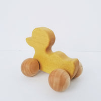 Yellow Duck toy with ball wheels on white background 