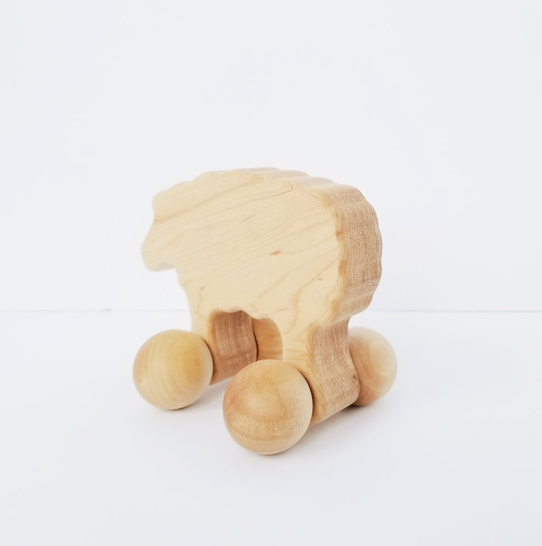 Light wood sheep toy with ball wheels on white background 