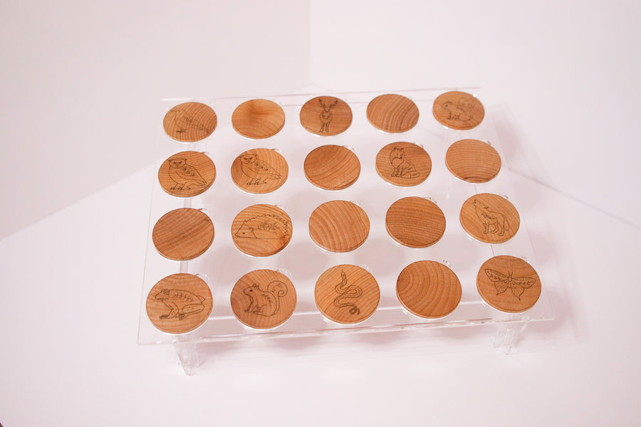 Matching game with stylized woodland animals laser burned on wooden coins being displayed on an acrylic stand.  Some of the coins are turned around backwards as if the game is in play